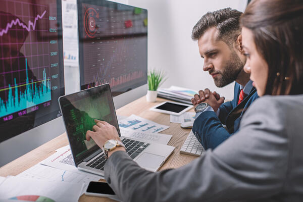 Bild vergr&ouml;&szlig;ern: Seitenansicht von Computersystemanalysten mit Diagrammen auf Computerbildschirmen w�hrend der Arbeit im B�ro
