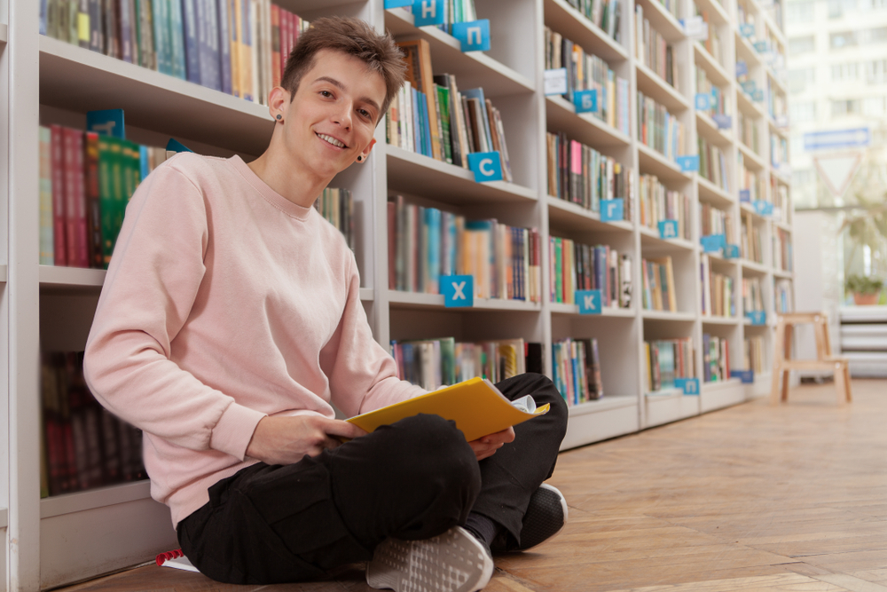 Ein junger Student liest ein Buch in der Bibliothek
