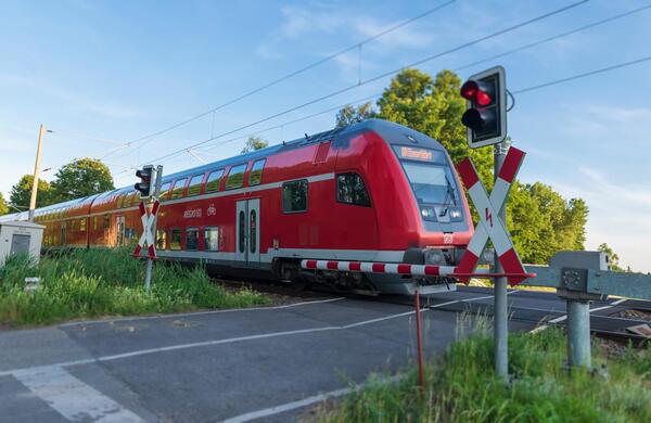 Bild vergr&ouml;&szlig;ern: Ein Regionalexpress �berequert einen Bahn�bergang mit Schranken.