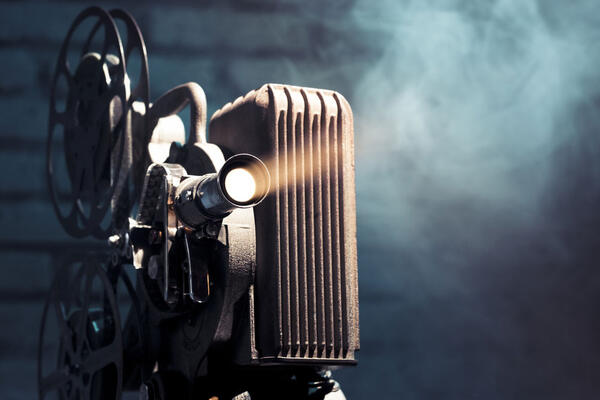 Bild vergrößern: ein alter Kinoprojektor wirft sein Licht in einen von Nebel umgehbenen Raum