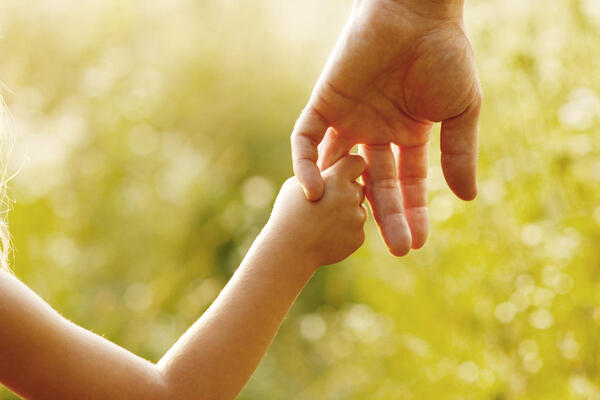 Bild vergrößern: Kinderhand hält sich am Finger eines Erwachsenen fest.
