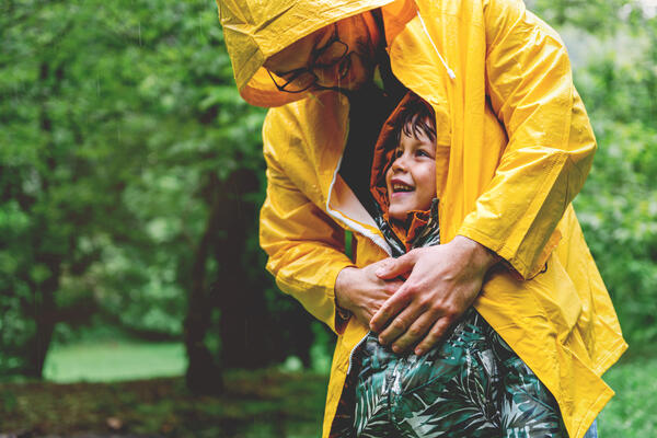 Kind wird von Vater geschützt, Regenmantel